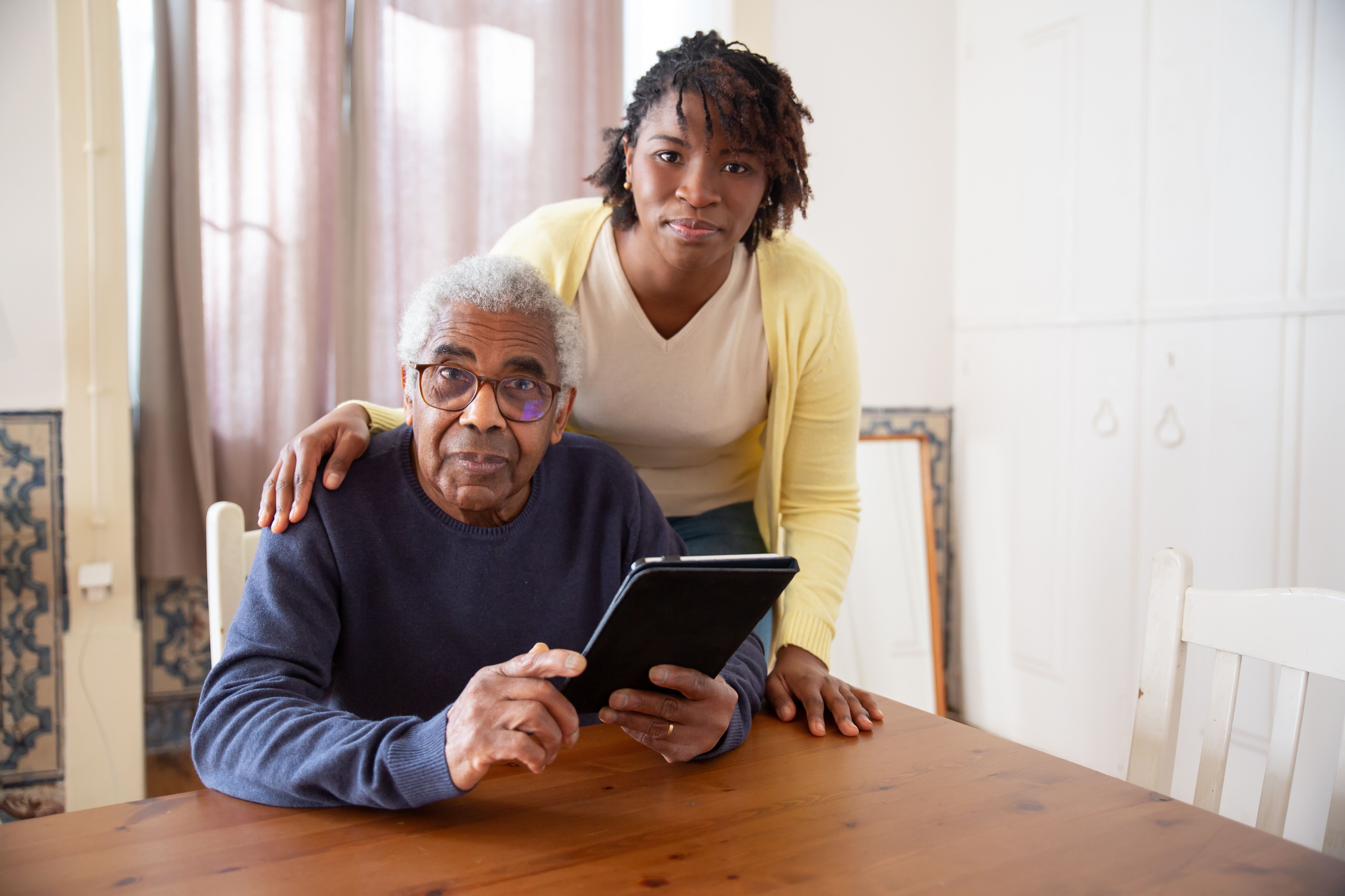 Pflegekraft berät einen Senior zuhause